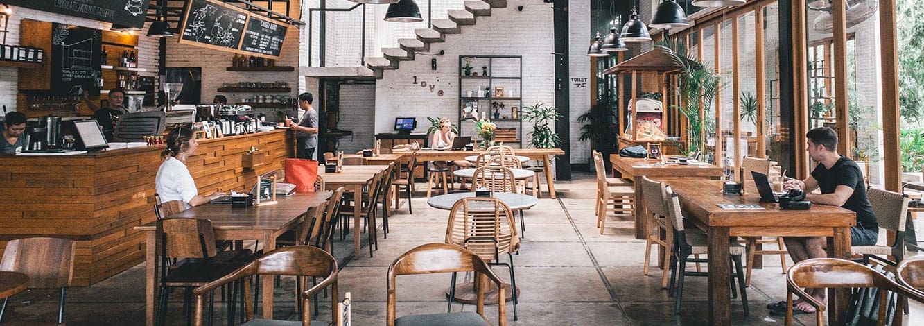 Spacious modern cafe with wooden tables and patrons Spacious modern cafe with wooden tables and patrons